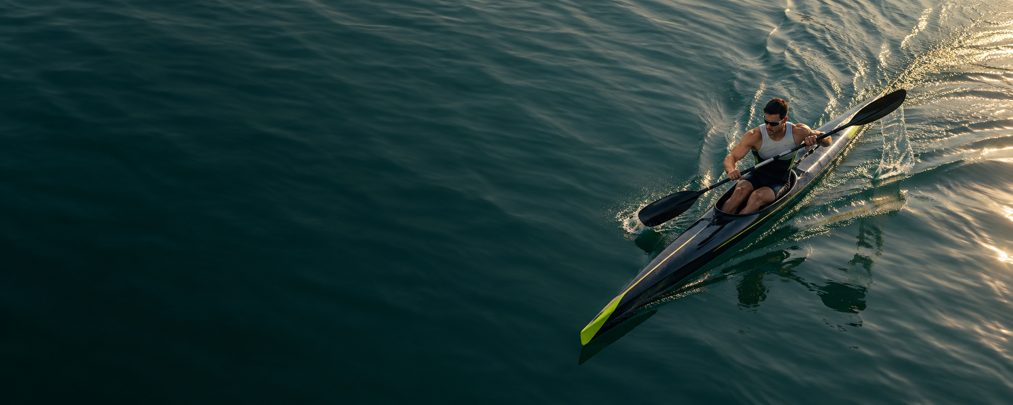 Piragüista en un kayak de competición sobre agua verde, visto desde el aire